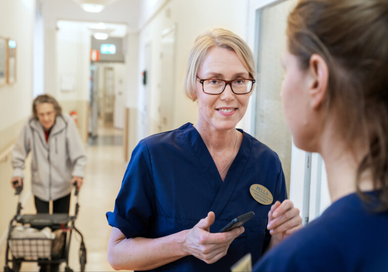 En sköterska pratar med en patient i en korridor.