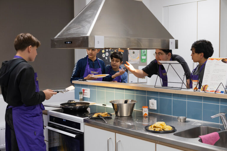 En grupp människor i ett kök som lagar mat.