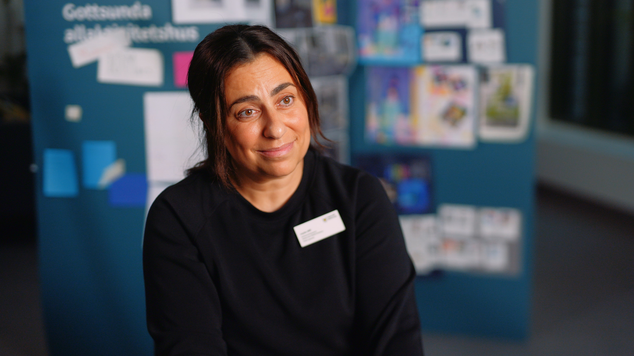 En kvinna sitter framför en blå skylt.