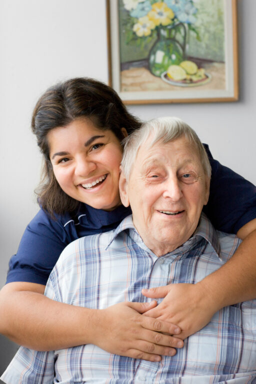 Äldre man kramas om av kvinna från hemtjänst