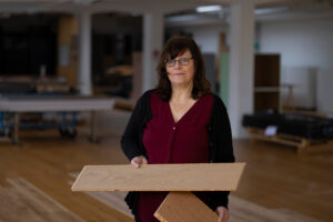 En kvinna håller i en träbit i ett rum.